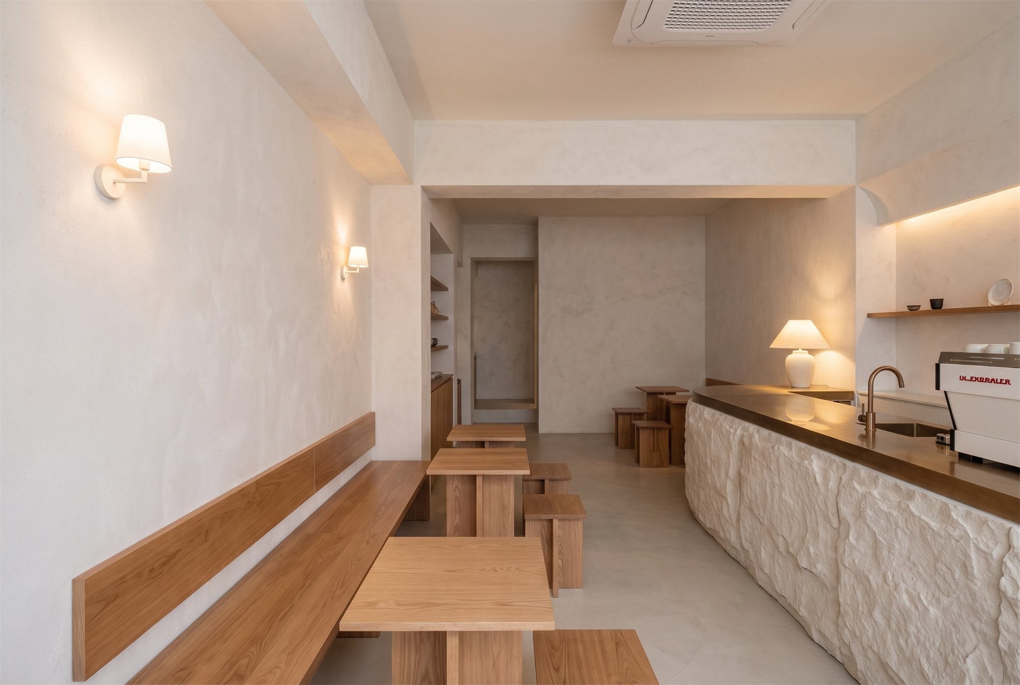 LAYERED GROUND — café interior with a sculptural stone counter under low warm light