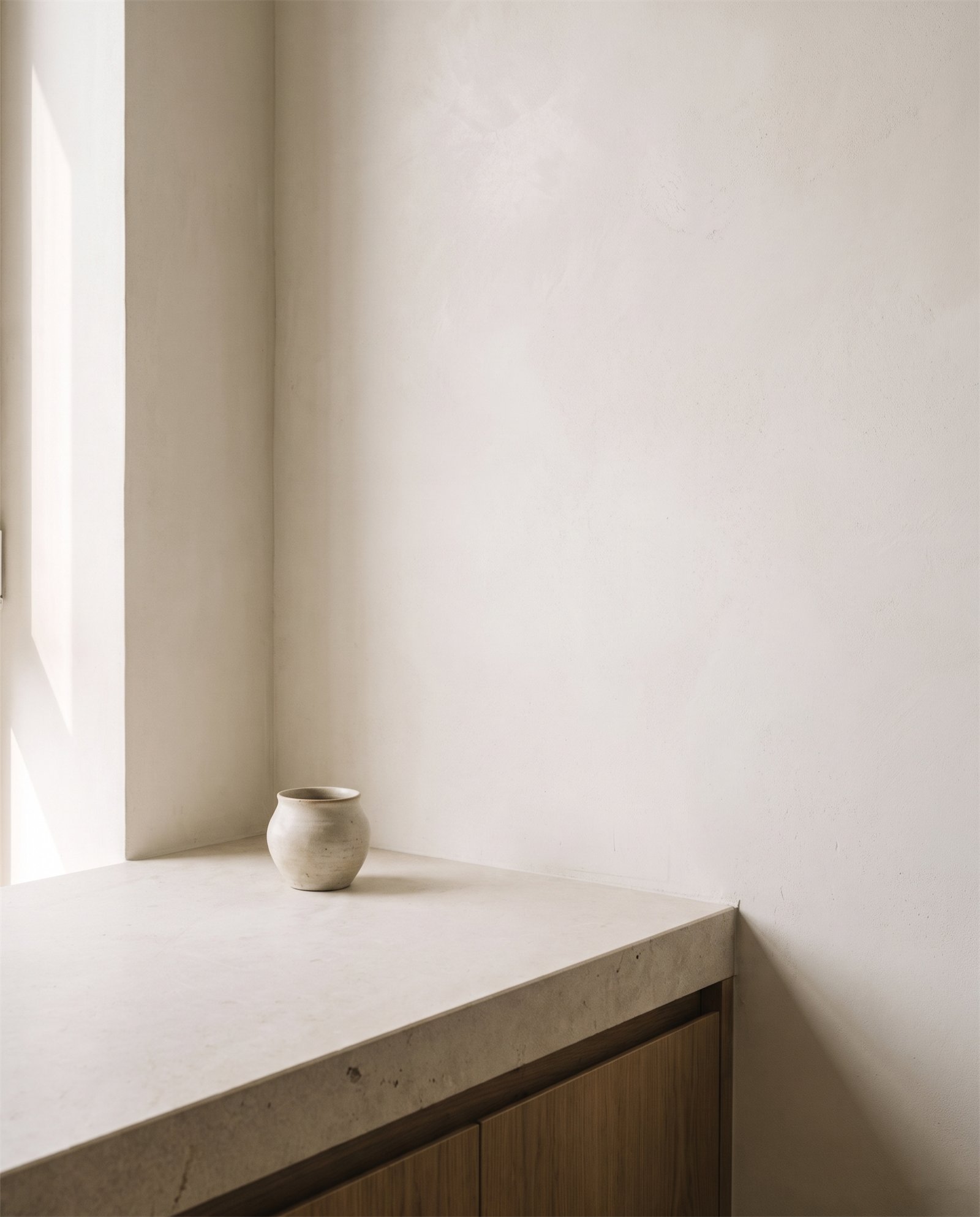 SOFT LIGHT — detail of a limestone kitchen counter meeting lime plaster wall